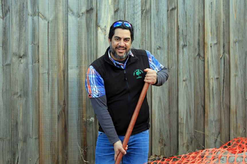 A man standing in a hole with a shovel