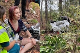A woman is covered in blood in bushland after her car was rammed and flipped.