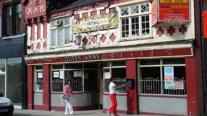 A street shot of the front of a historic red and white English pub.