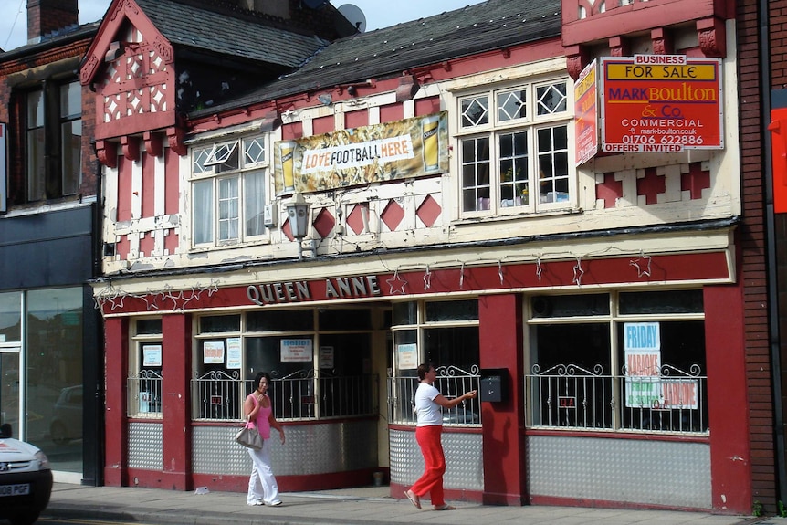 A street shot of the front of a historic red and white English pub.