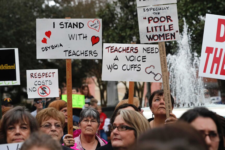 Women hold protest signs in support of teacher Deyshia Hargrave, who was arrested for questioning a superintendent's pay rise.