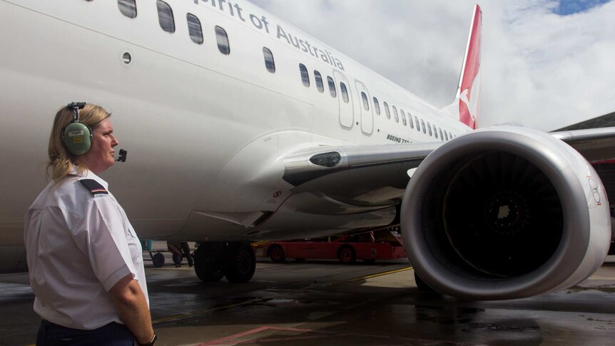 Kylie Morgan stand besides a Qantas plane