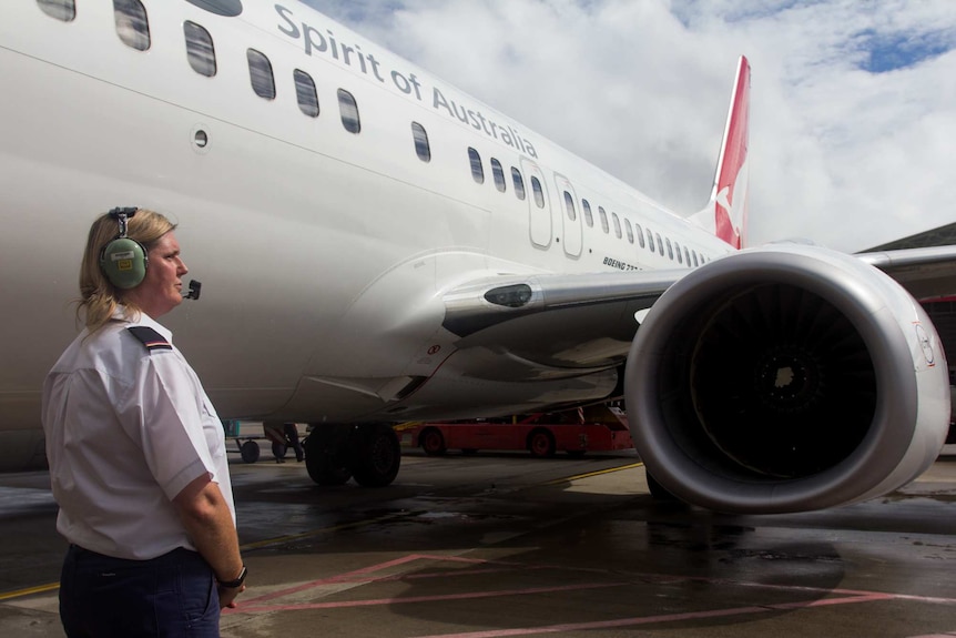 Kylie Morgan stand besides a Qantas plane