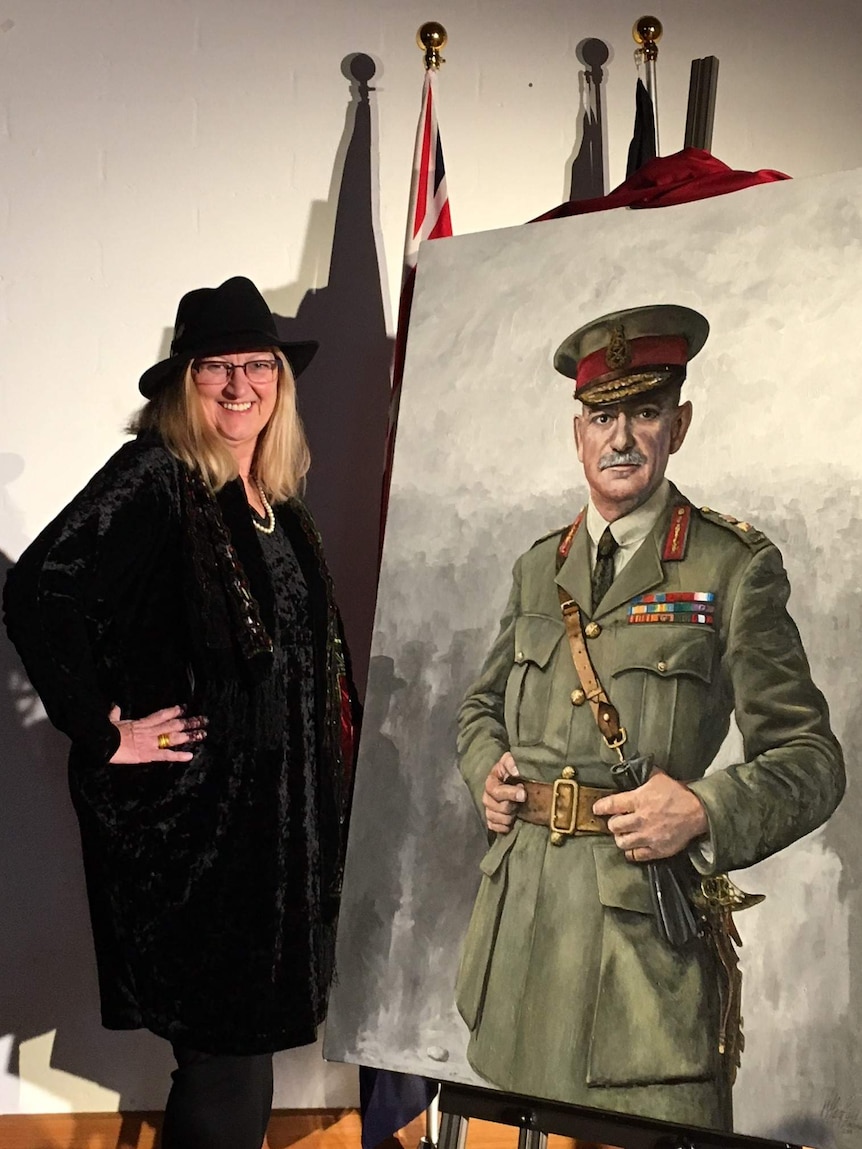 A woman in a hat stands next to a painting of a military man.