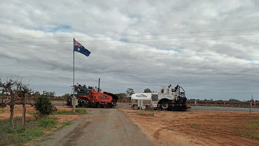 Image of a driveway with clouds in the sky and two large vehicles.