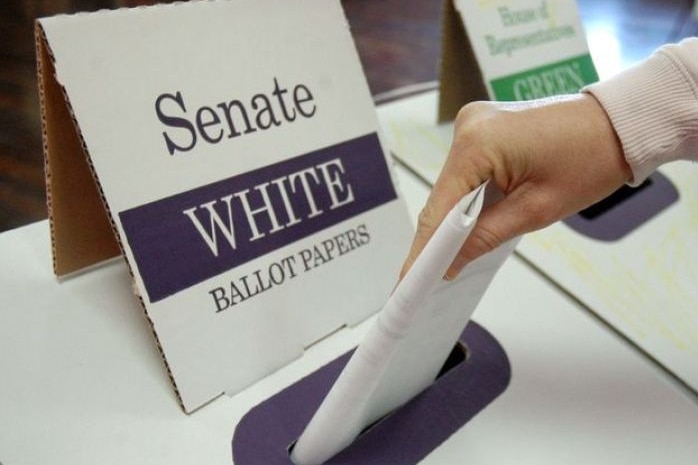 A close-up image of a woman's hand putting a ballot paper into a Senate ballot box.