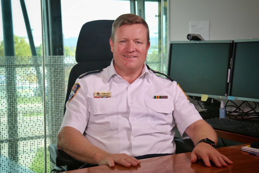 A man smiles while seated at his desk.