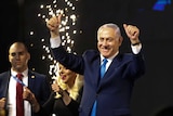 Benjamin Netanyahu wears a blue suit and has his thumbs up as fireworks go off in the background