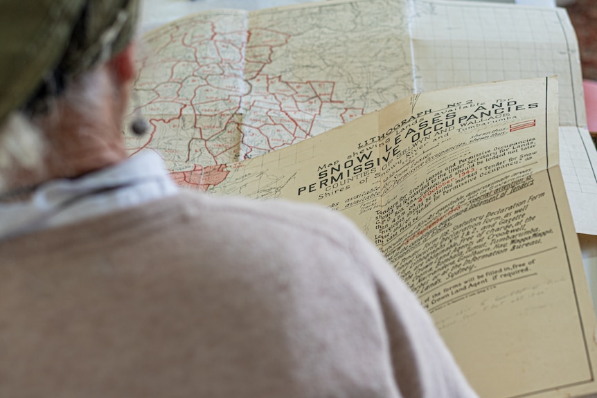 Looking over the shoulder of a woman looking at an old snow lease map.