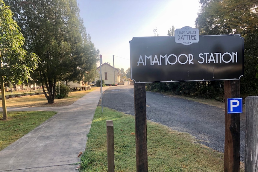 Mary Valley Rattler Amamoor station sign with railway buildings behind it.