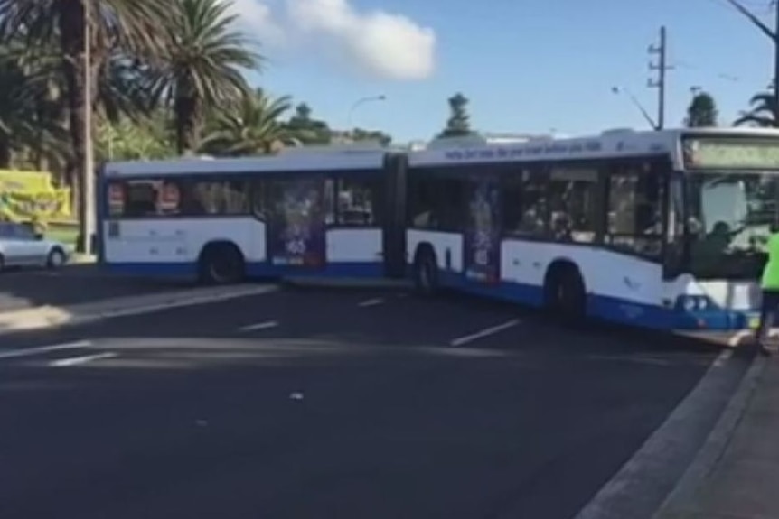 A bus straddles a median strip and blocks several lanes of traffic on a road