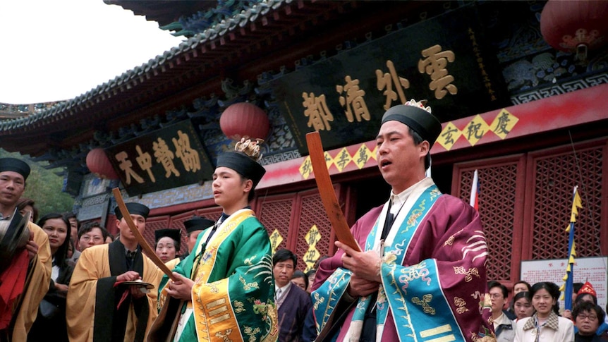 Daoist priests conduct prayers for a group of elderly pilgrims