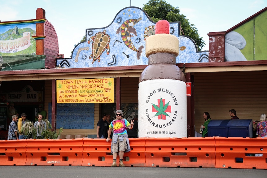 Man poses outside inflatable cannabis tincture in Nimbin