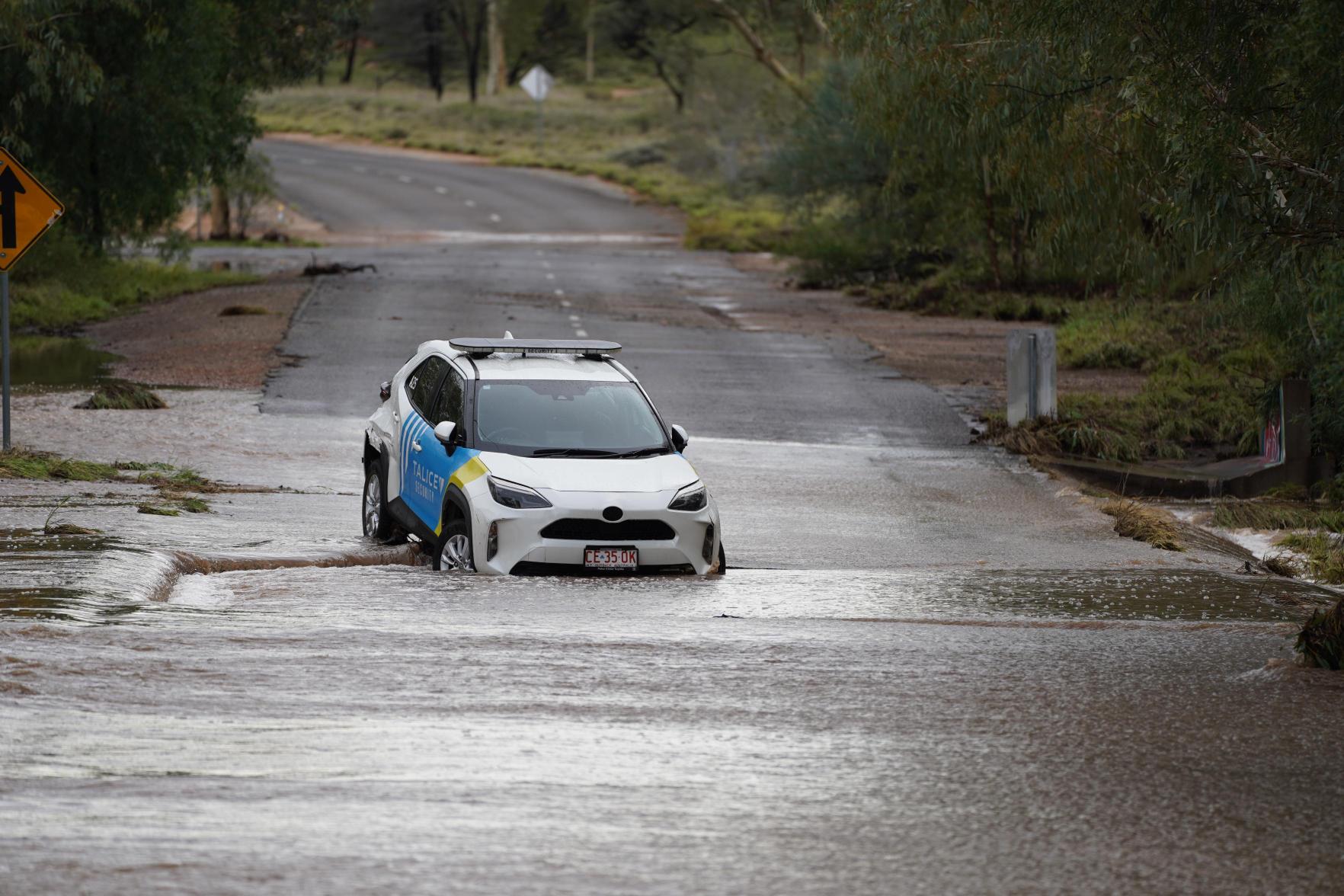 Um safety car azul e branco abandonado em uma estrada coberta por enchentes. 