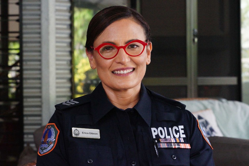 A photo of a smiling female police officer wearing red glasses.