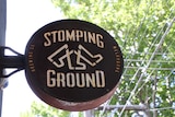 A sign saying Stomping Ground with logo featuring three legs.