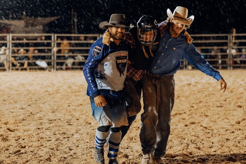 Two men help a female bull rider from the ring after she was injured in a fall.  