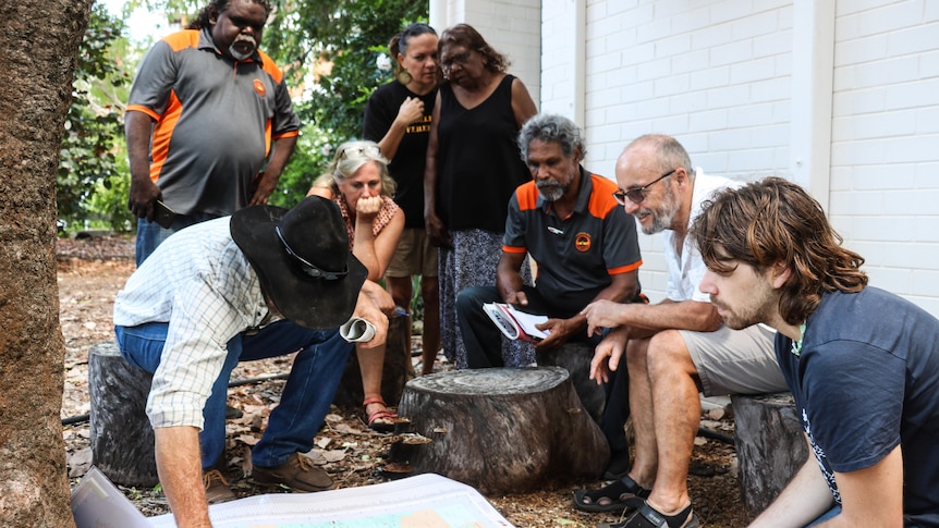 A group of people stand around a map.