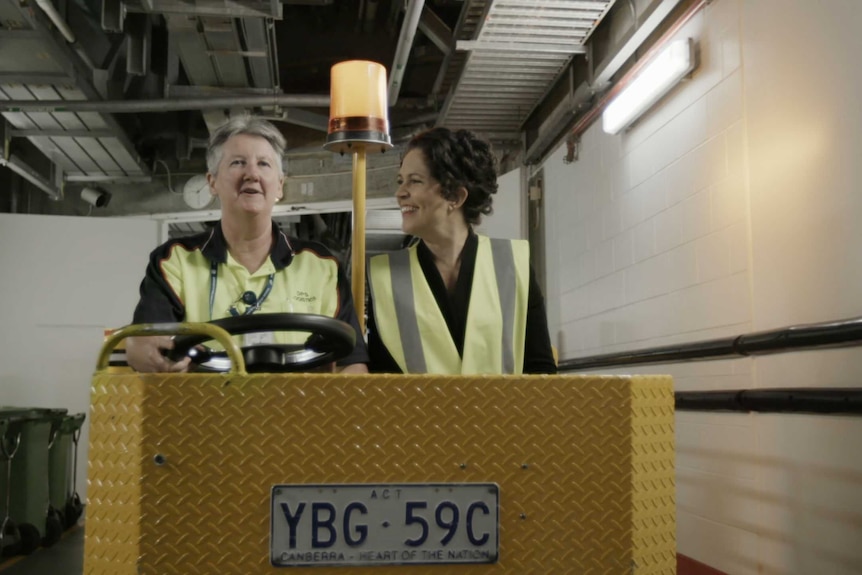 Two women drive underground in a cart