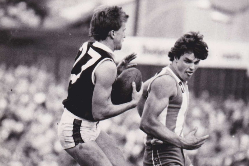 Two men return to the ground after jumping for a mark in a VFL game.