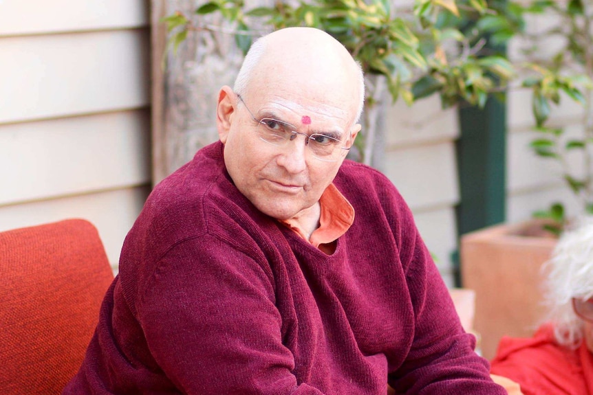 Russell Kruckman sits on a chair and looks to the left of frame.