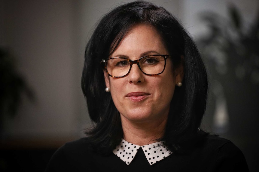 Dr Caitlin Curtis wears a black top and glasses.