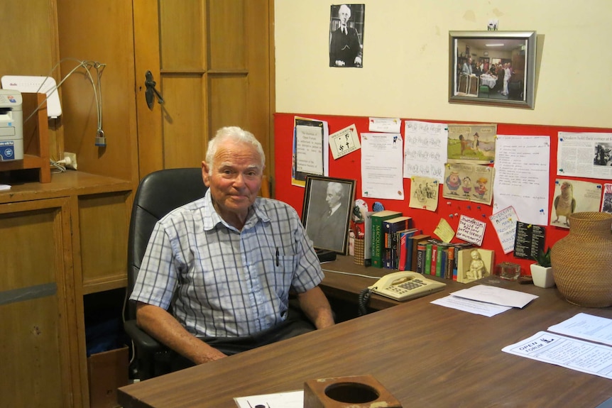 One of the founding members of the NSW Humanist Society, Fred Flatow, sits at his desk surrounded by books and framed photos.