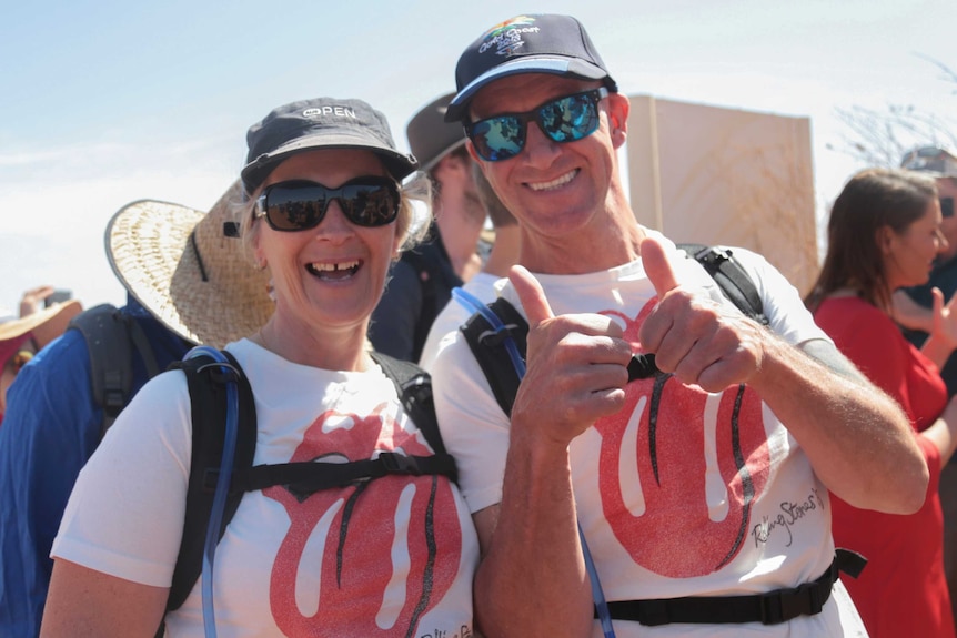 Katrina and Paul Ballinger smile at the camera. Paul is giving two thumbs up and the couple looks excited.