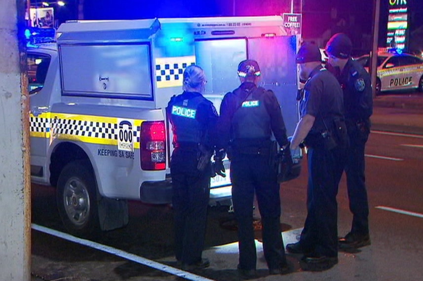 Four SA Police officers standing behind a police vehicle