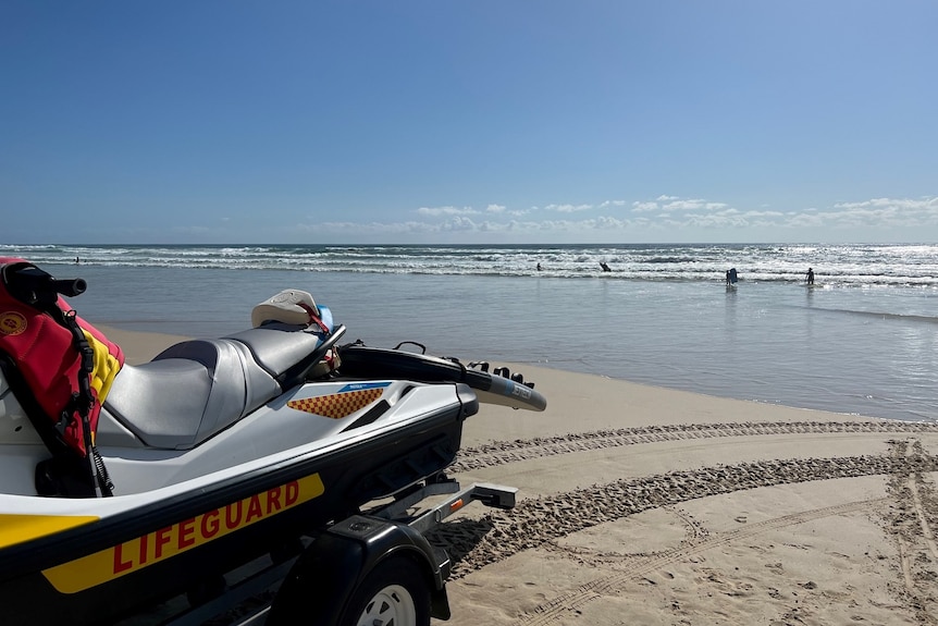 A lifeguard jet ski with west sand and surf in the background.