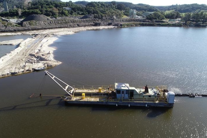 Aerial shot of a pond with a boat conducting a dredging operation.