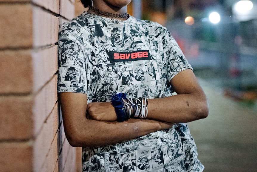 The torso of a young girl, wearing a black and white t-shirt and plastic bracelets on one wrist.