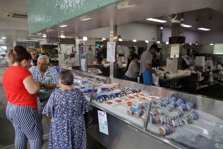 People look at fish and seafood in display cabinets for sale.