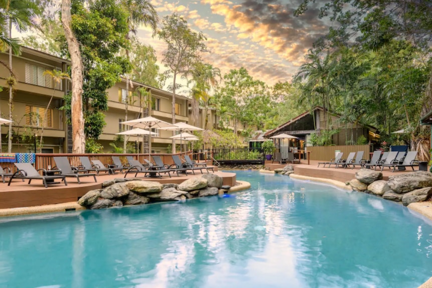 Resort-Pool umgeben von Bäumen und Liegestühlen