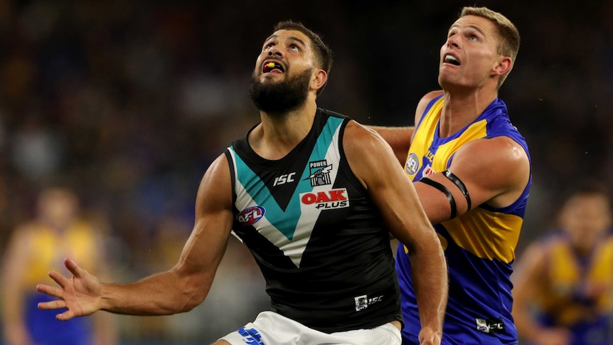 Paddy Ryder stands with his right hand outstretched looking up at the sky with Nathan Vardy behind him.