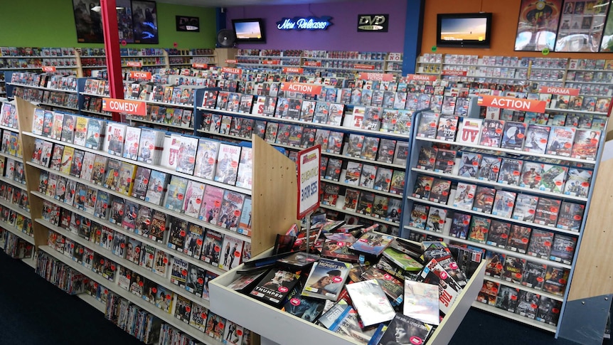 Wide shot of video rental store with shelves full of DVDs.