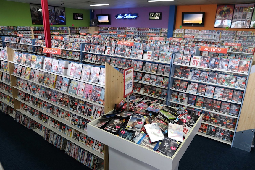 Wide shot of video rental store with shelves full of DVDs.
