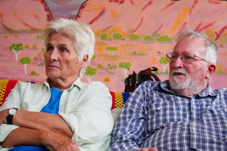 A Caucasian woman and man listen carefully at a community hall.