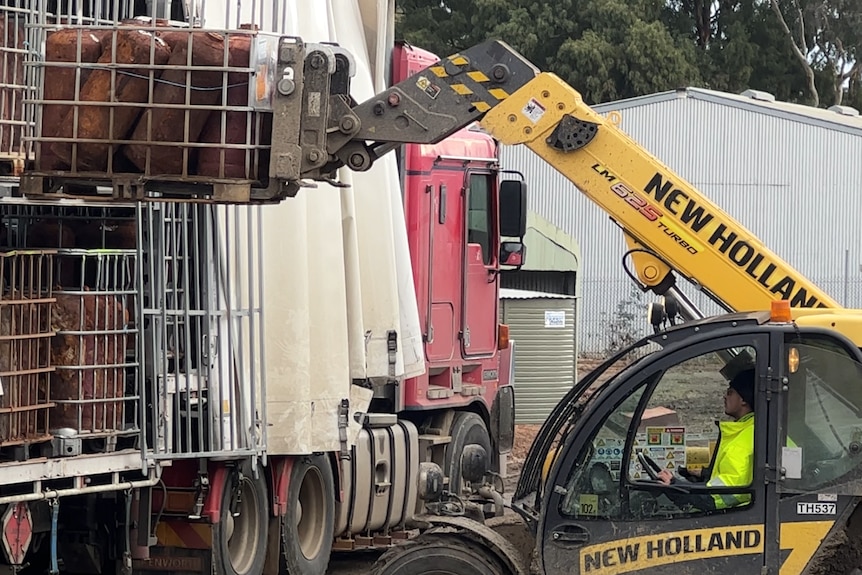 A forklift removes a cage full of empty gas cylinders from a B-Double truck