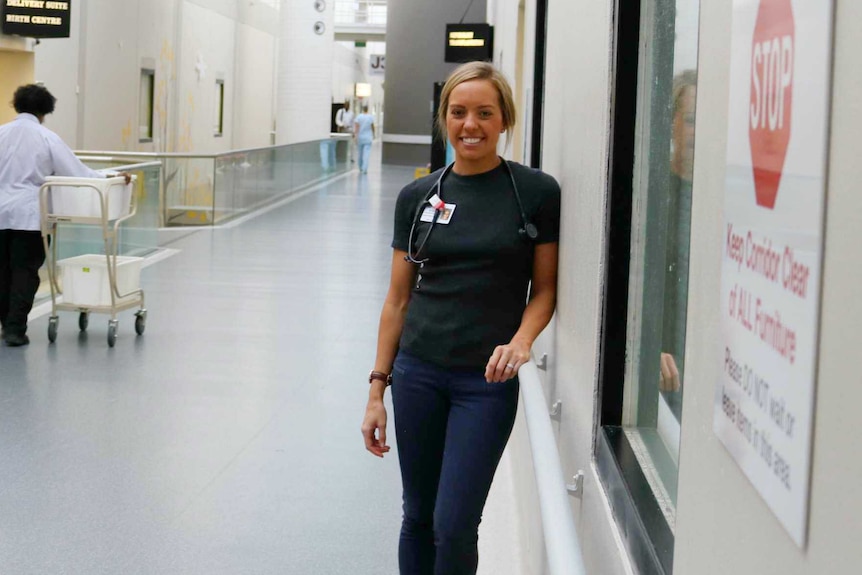 A young Indigenous woman with blonde hair standing in the corridor of a hospital.