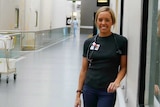 A young Indigenous woman with blonde hair standing in the corridor of a hospital.