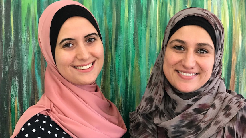 Two smiling ladies wearing hijabs pose for the camera