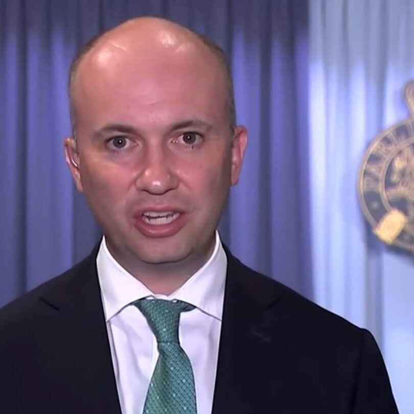 A bald man in a suit and tie looks at the camera from New South Wales Parliament