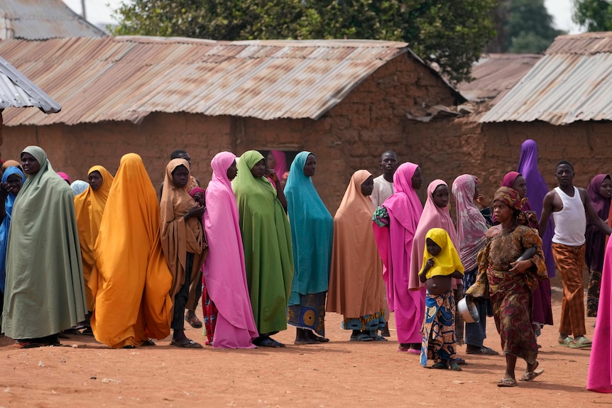 People wearing bright coloured clothing stand together at a Nigerian school.