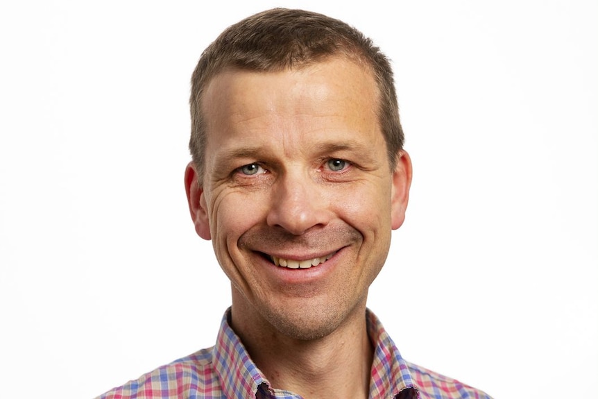 A profile of a man wearing a checked shirt.