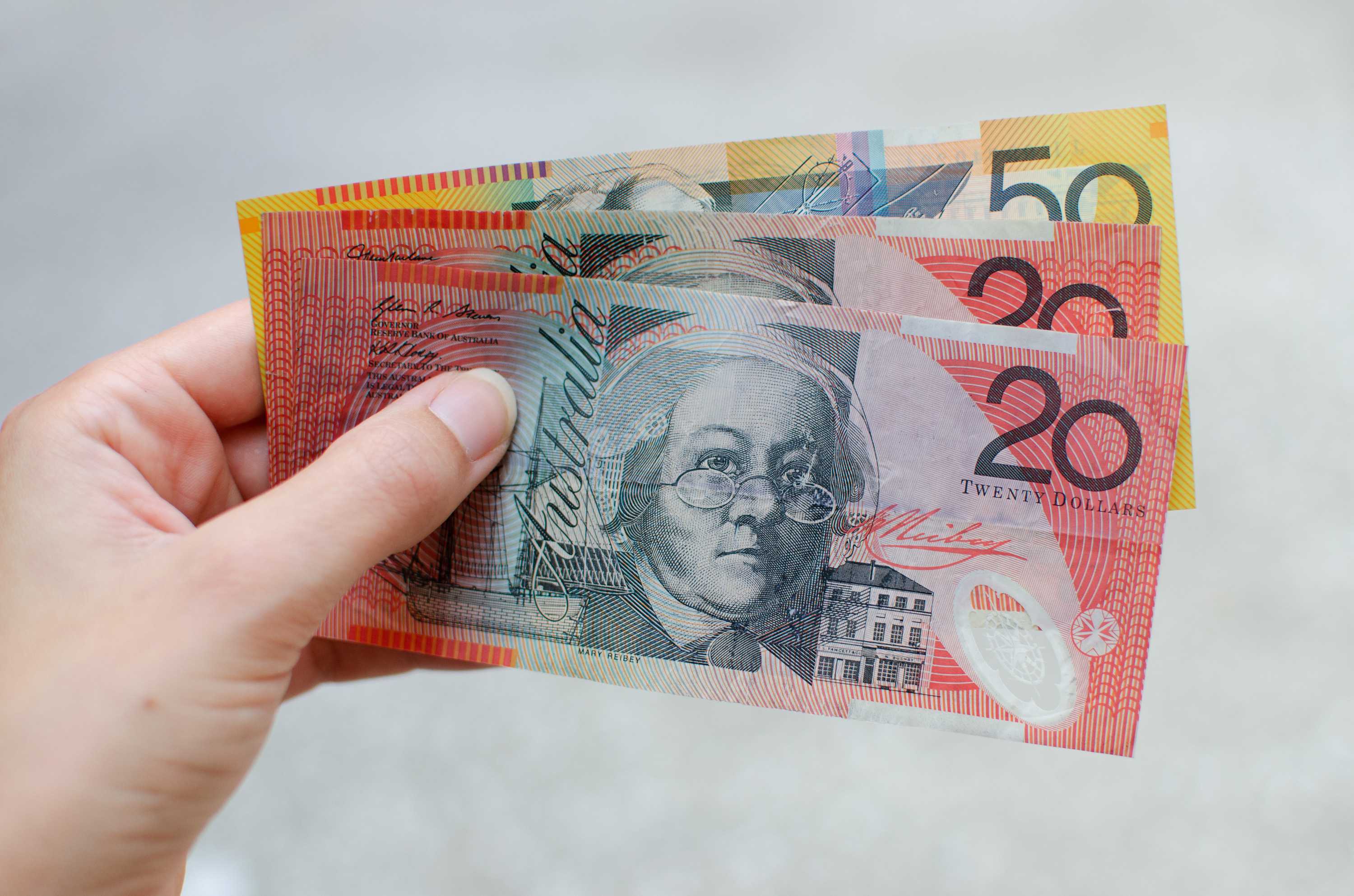 A woman holds a $50 note and two $20 notes for a story about superannuation.
