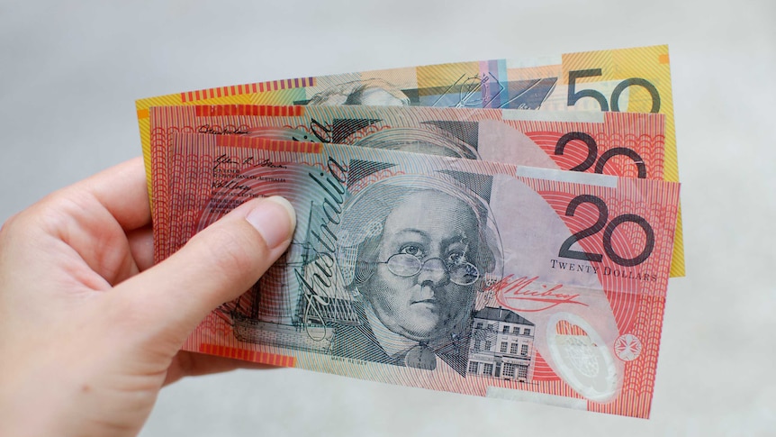 A woman holds a $50 note and two $20 notes for a story about superannuation.