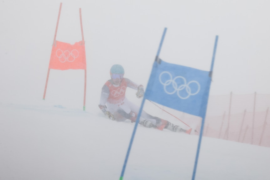 A skier weaves between Olympic slalom posts in snow-blind conditions down a slope