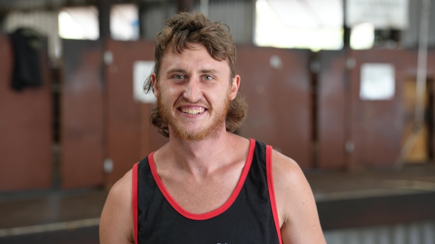 a man with a mullet in a blue singlet 