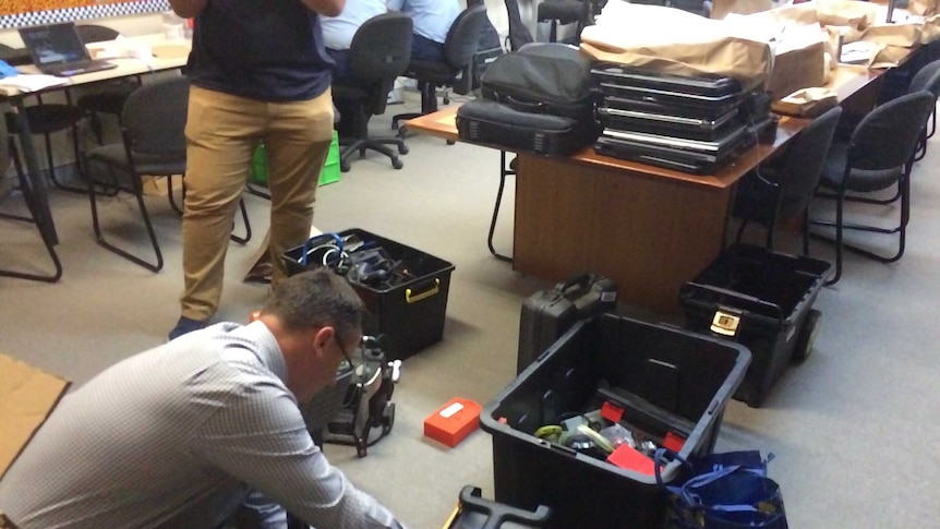Police kneeling over boxes of tools